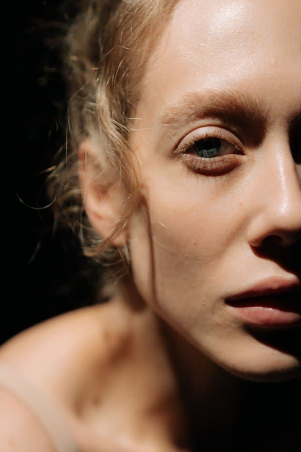 A moody low-key half-face portrait with fair skin.